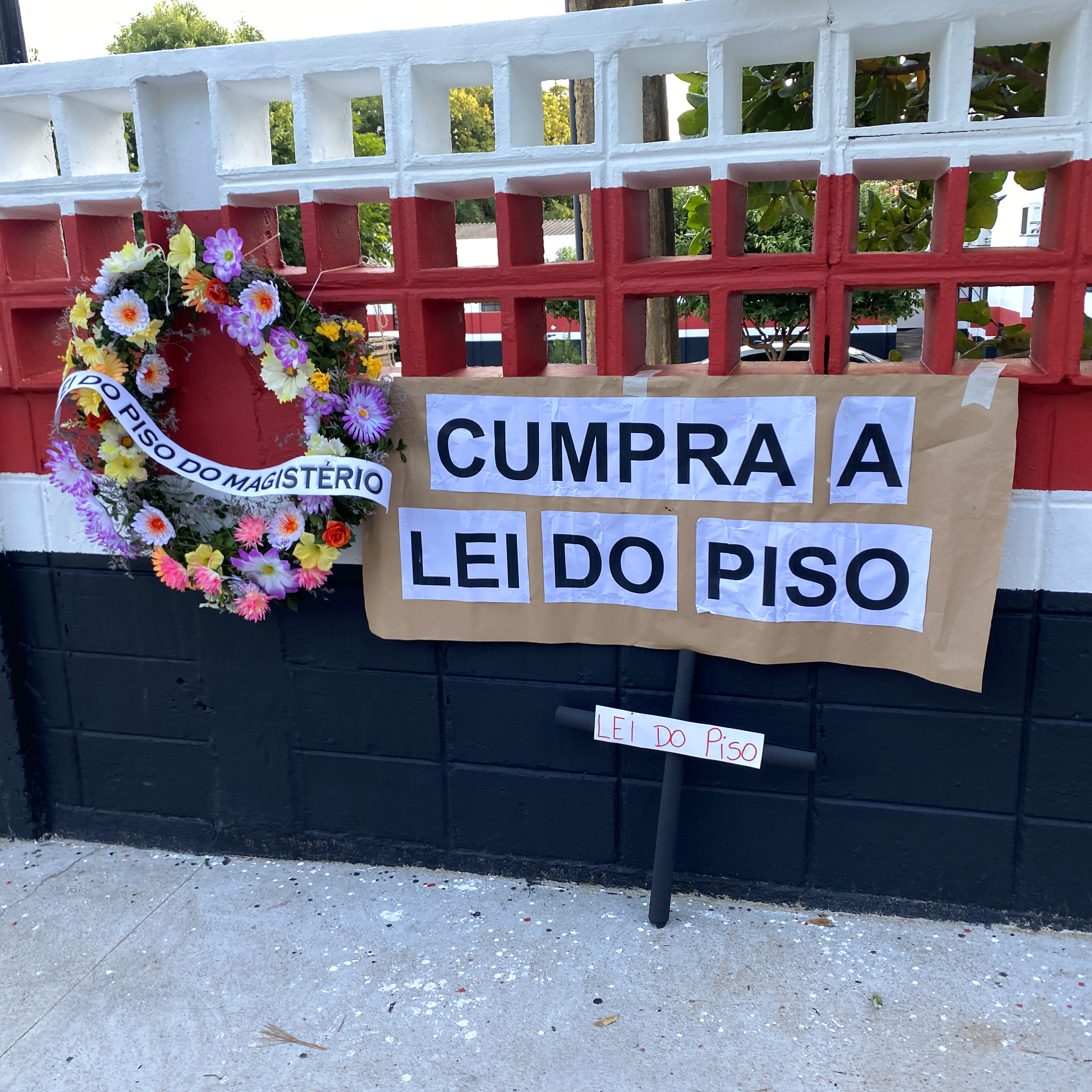 Coroa de flores, cruz e cartaz com frase “cumpra a lei do piso” foram afixados em frente à Seduc