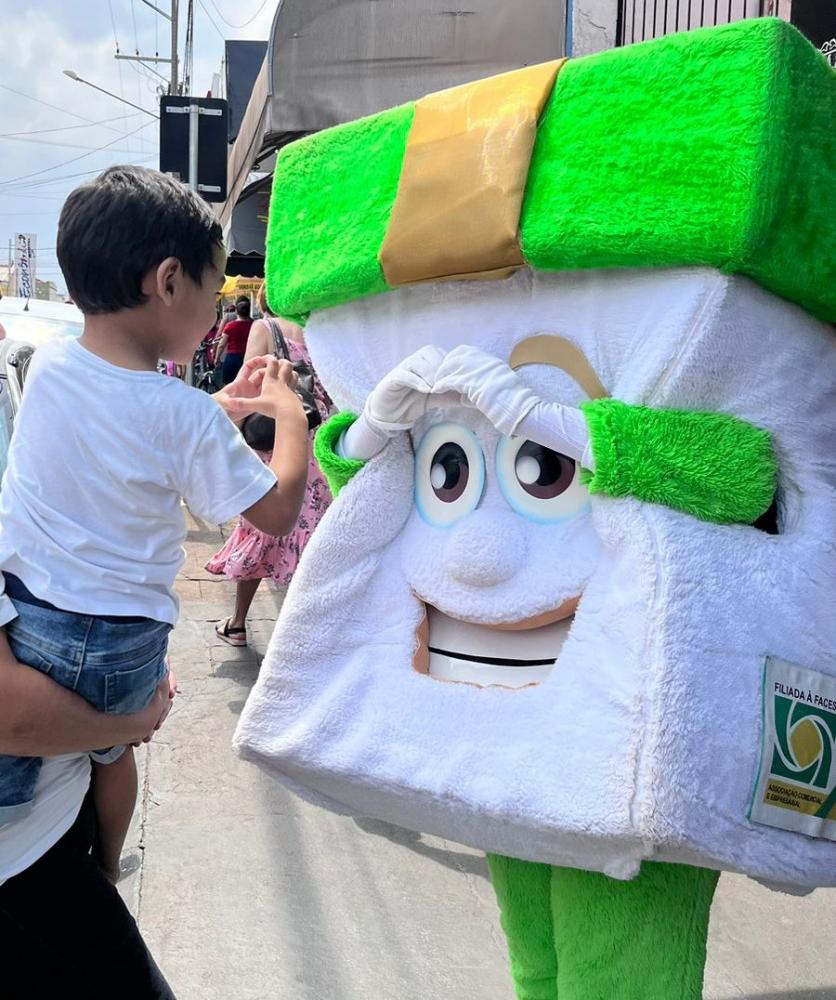Acezinho, mascote da ACE de Pirapozinho, interagindo com as crianças no comércio da cidade