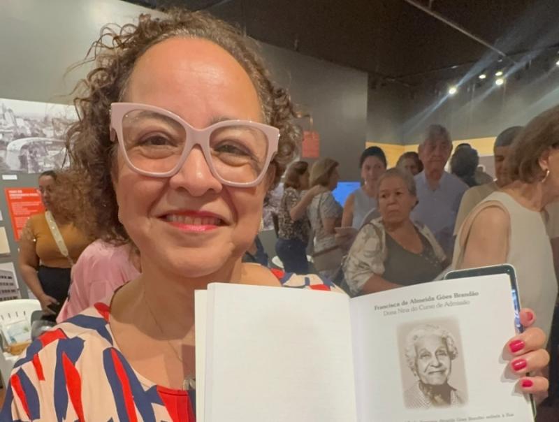Sonia Pelegrini, diretora da Escola Professora Francisca de Almeida Góes Brandão, exibe o capítulo do livro do professor Benjamin, com a homenagem à patrona da escola