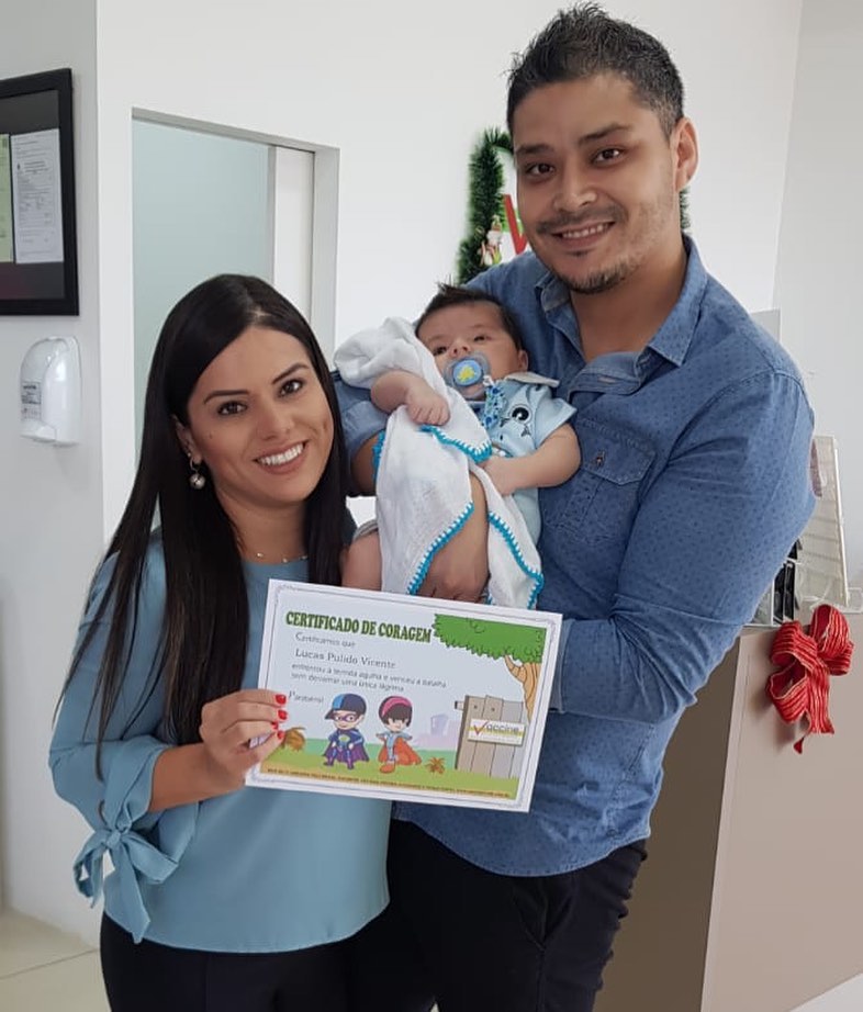 Pequeno Lucas, com os pais Ivan e Aline Pulido, recebe o certificado coragem de vacinação da Vaccine Care